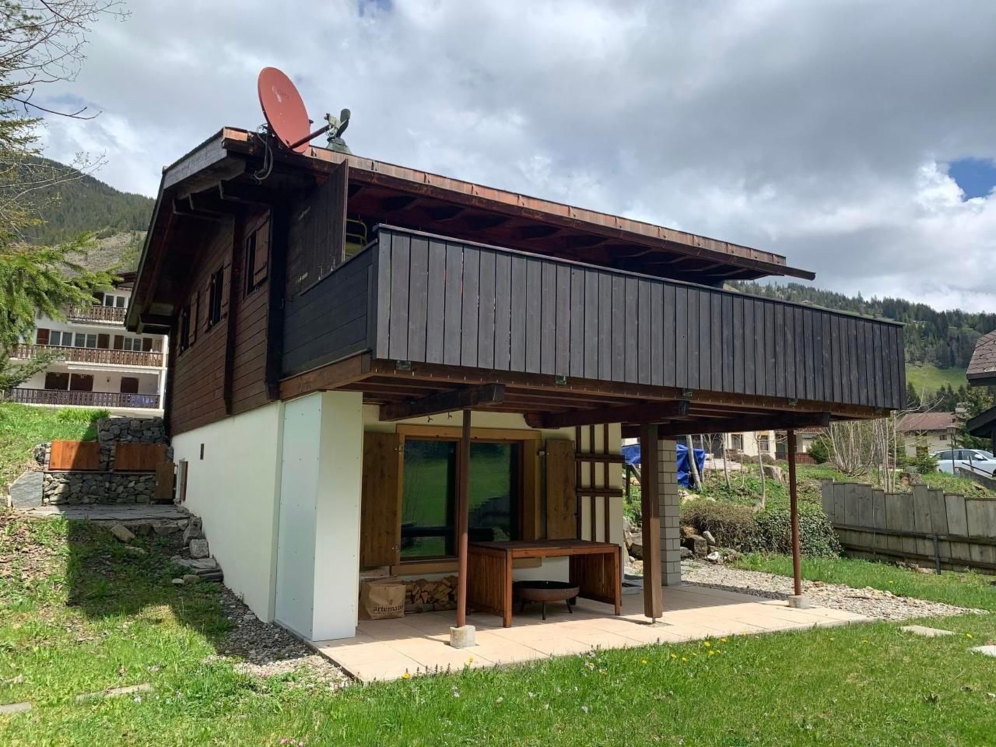 Une maison moderne à deux étages, avec une façade en bois, un balcon et une antenne parabolique.