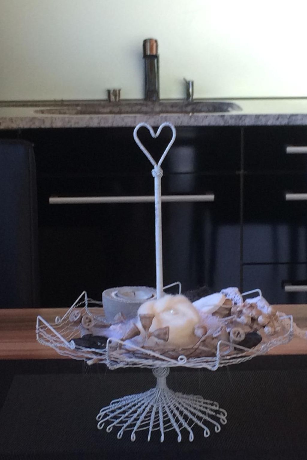 A wire fruit basket with a heart-shaped topper on a table.