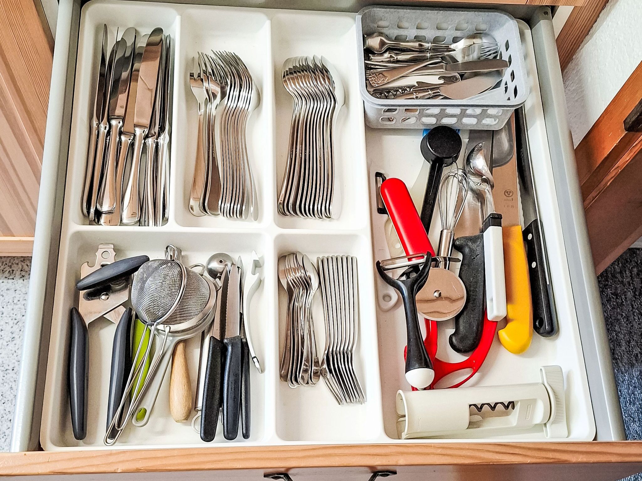 Un cajón con diversos utensilios de cocina organizados en compartimentos.