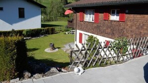 Asuinkiinteistö, jossa on hyvin hoidettu nurmikko, puinen aita ja avoin näkymä kumpuilevaan maisemaan.