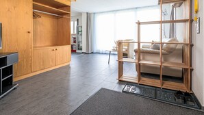 A modern living room with a wooden cabinet, a glass shelf unit, and a sofa. - Schrattewohnung Birkenhof (4-Bett) by Interhome (Sörenberg)