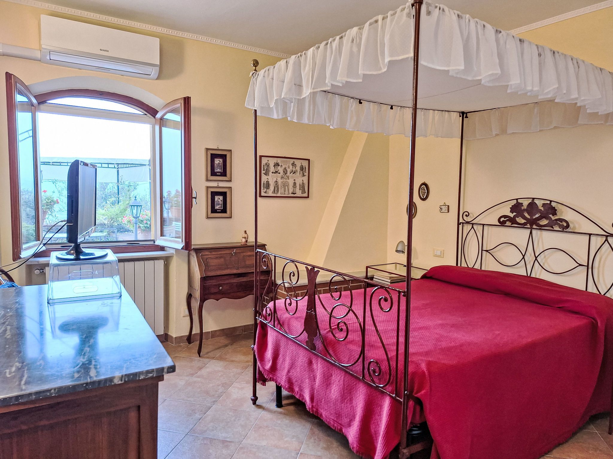 Una habitación con cama, escritorio, ventana y aire acondicionado instalado en la pared.