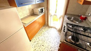 A compact kitchen with blue cabinets, a microwave, a sink, and a gas stove. - VILLA CASTORINI - B2 4+0 - B3003C (Bibione Pineda)