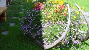 Un giardino con un fioriere in legno pieno di fiori colorati e una struttura in legno ad arco.