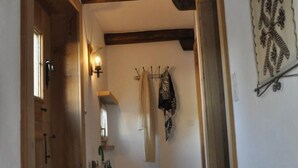 Un corridoio con porte in legno, pavimento in pietra e una lampada a parete.