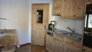 Una cucina compatta con mobili in legno, lavastoviglie integrata e macchina da caffè.