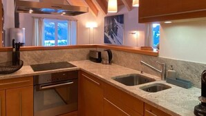 A modern kitchen with granite countertops, stainless steel appliances, and wooden cabinetry. - Chesa Baia by Interhome (La Punt-Chamues-ch)