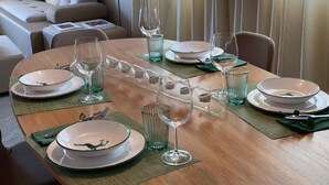 A dining table set for six with clear glassware and plates, a green placemat, and a glass wine decanter. - Chesa Baia by Interhome (La Punt-Chamues-ch)