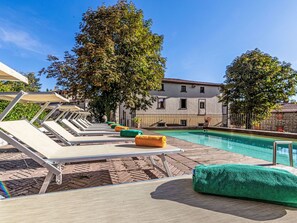 A poolside area with sun loungers, a pool, and a building in the background. - Wohnung in einer alten Villa mit Schwimmbad by Interhome (Pratovecchio)