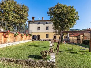 A two-story building with a garden, a swing set, and a wooden fence. - Wohnung in einer alten Villa mit Schwimmbad by Interhome (Pratovecchio)