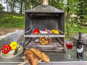 An outdoor grill with meat, vegetables, and bread, and a bottle of wine on a table. - Wohnung in einer alten Villa mit Schwimmbad by Interhome (Pratovecchio)