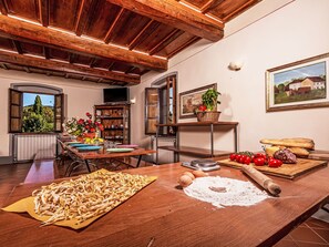 A rustic kitchen with wooden beams, a dining table set for a meal, and a view of the outdoors through an open door. - Wohnung in einer alten Villa mit Schwimmbad by Interhome (Pratovecchio)