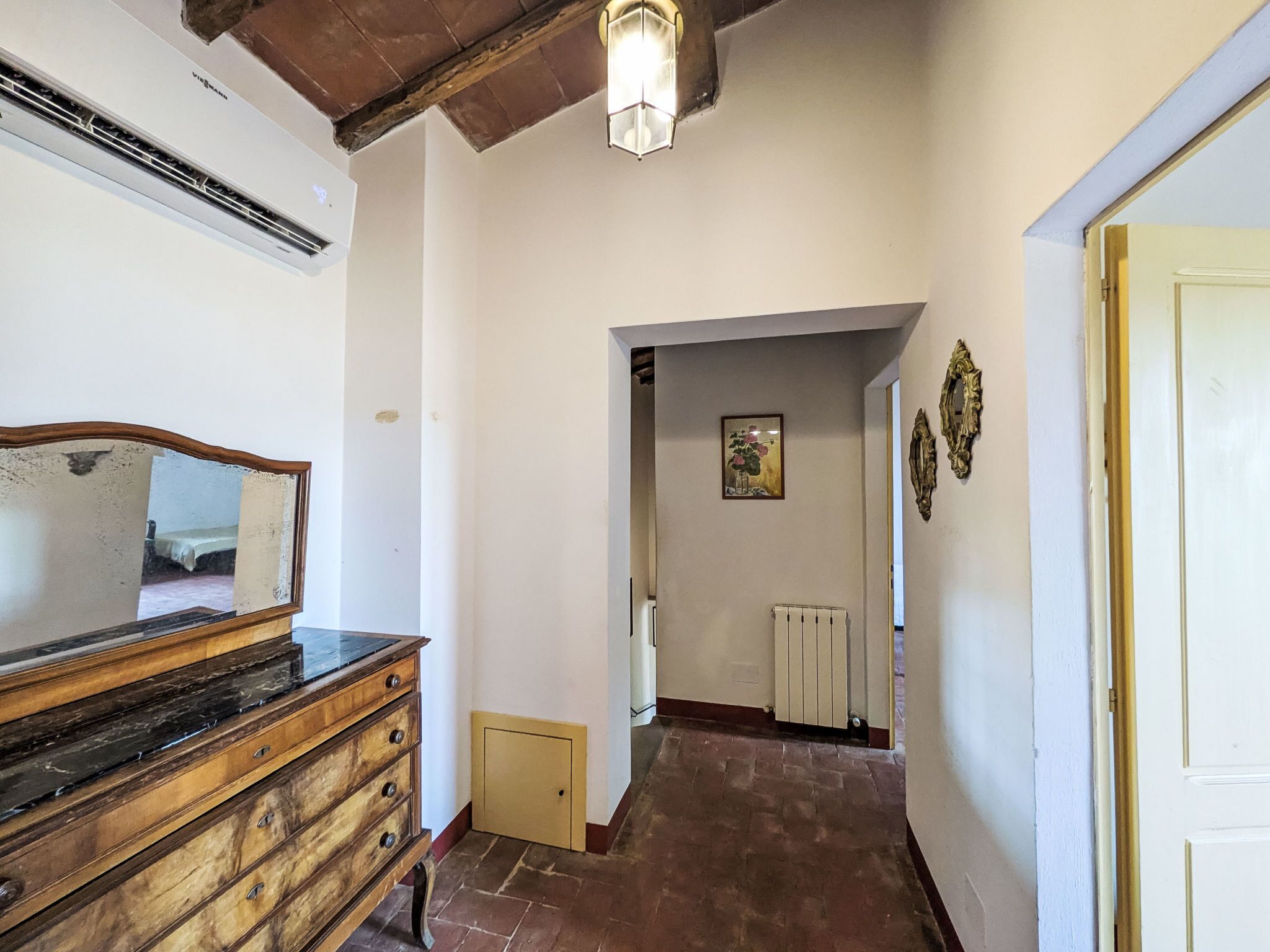 A hallway with a wooden dresser, a radiator, and a framed picture on the wall.