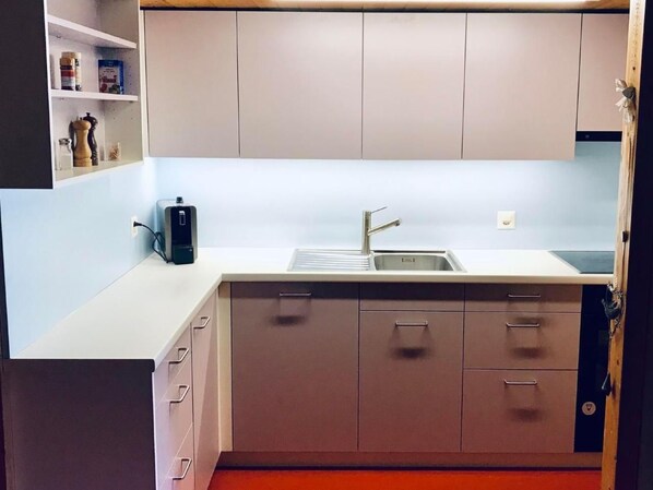 Een koelkast, een oven, een vaatwasser, kookgerei, borden en bestek