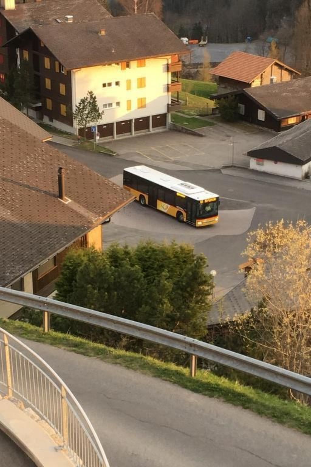 Un autobús estacionado en una zona residencial con casas y un edificio con garaje.