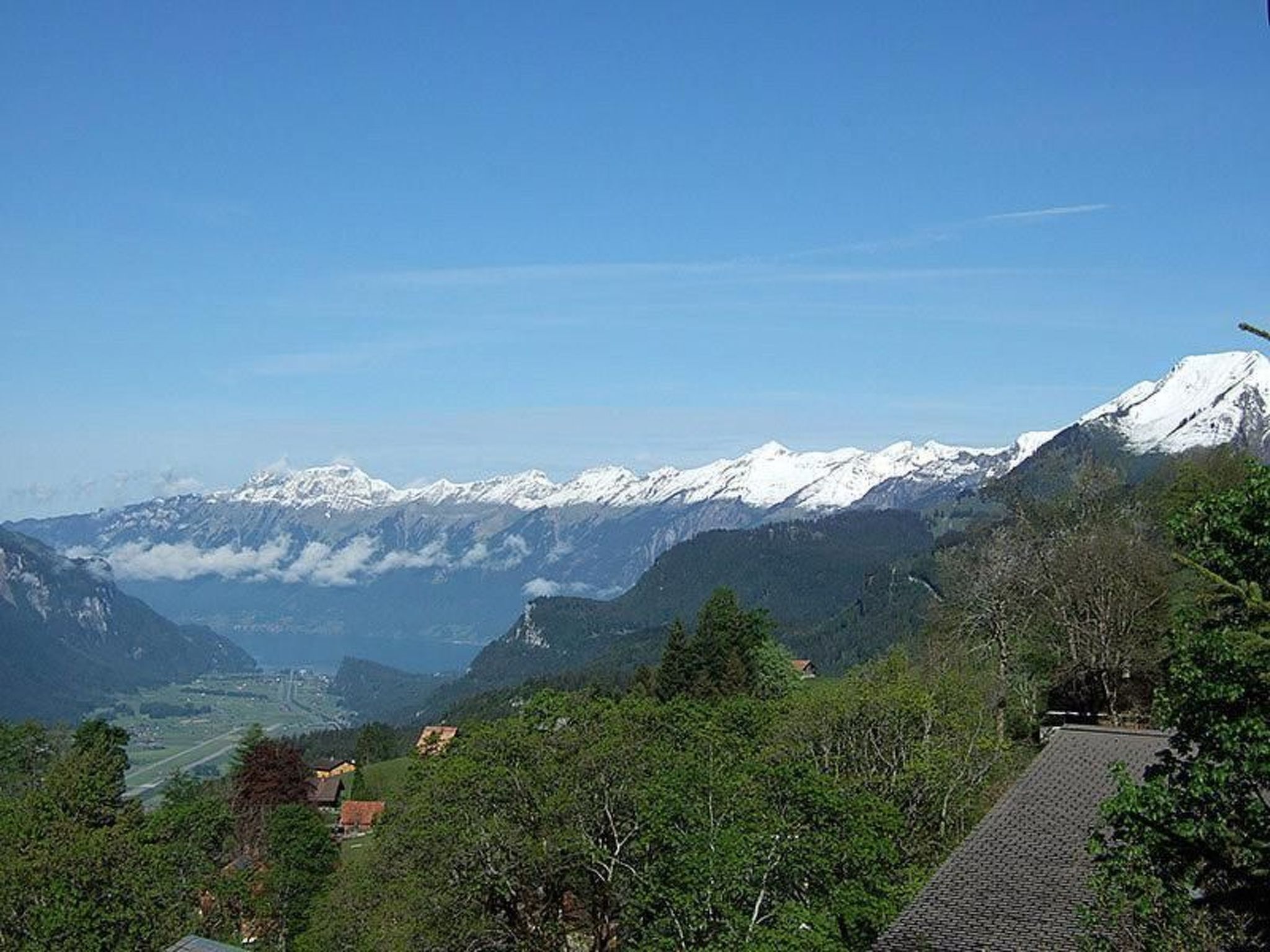 Un paisaje montañoso con picos nevados y un valle con casas.
