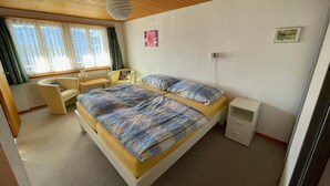 Un dormitorio con cama, una silla, un escritorio y una mesita de noche.