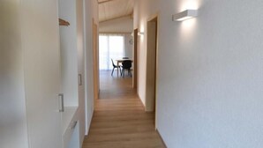 A hallway with wooden flooring and white walls, leading to a dining area with a table and chairs. - Gemeindematte „Sommer Bergbahnen inklusive“ by Interhome (Meiringen)