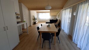 A spacious living area with a wooden dining table, black chairs, a sofa, and a television. - Gemeindematte „Sommer Bergbahnen inklusive“ by Interhome (Meiringen)