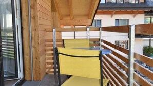 A wooden balcony with a yellow chair and a small table. - Gemeindematte „Sommer Bergbahnen inklusive“ by Interhome (Meiringen)