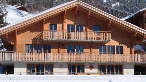 A multi-story wooden building with balconies, large windows, and a snow-covered roof. - Schaad 8-Bettwohnung by Interhome (Hasliberg)
