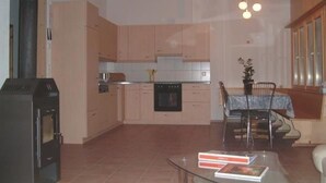 A compact kitchen with a dining area, a built-in oven, and a dining table with chairs. - Schaad 8-Bettwohnung by Interhome (Hasliberg)