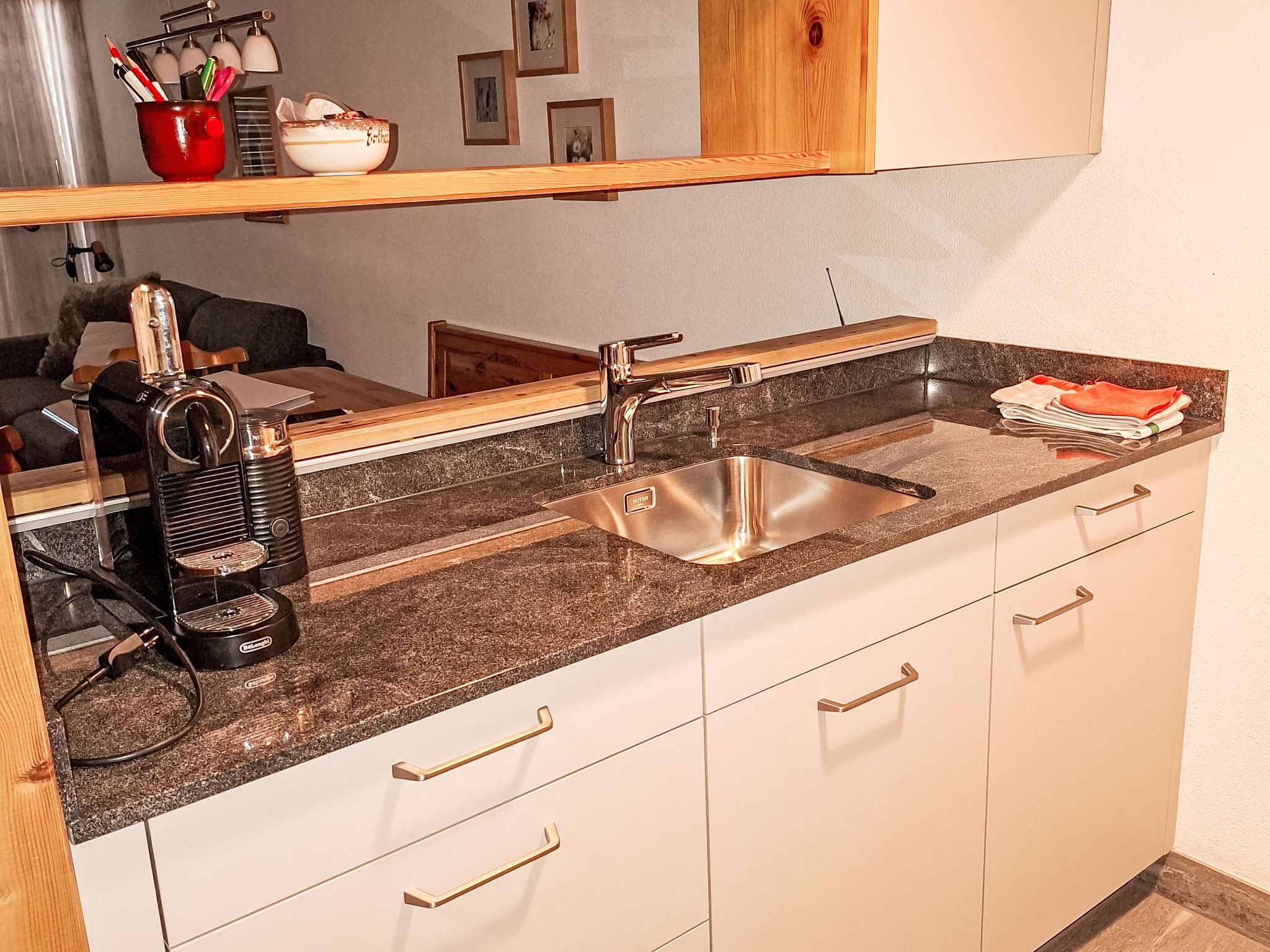 Une cuisine équipée d’un évier en acier inoxydable, d’une machine à café et d’un plan de travail en bois.