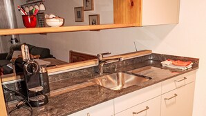 Una cocina con un lavamanos de acero inoxidable, una cafetera y una encimera de madera.