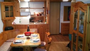 Una mesa de madera con platos, una botella de vino y un cuenco rojo.