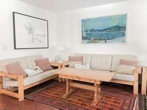 Una sala de estar con un sofá de madera, una mesa de centro y dos cuadros en la pared.