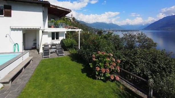 A white house with a pool, a patio, and a view of a lake and mountains. - Casa Leula by Interhome (Ronco sopra Ascona)