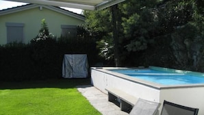 A swimming pool with a covered area, a grassy lawn, and a chair. - Casa Leula by Interhome (Ronco sopra Ascona)