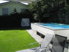 A swimming pool with a covered area, a grassy lawn, and a chair. - Casa Leula by Interhome (Ronco sopra Ascona)