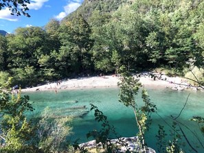 Eine natürliche Landschaft mit einem klaren, türkisblauen See, umgeben von dichtem Grünwald und felsigem Gelände.