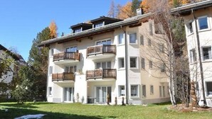 A multi-story hotel with balconies, a flat roof, and a garden area. - Chesa Semnadur H8 by Interhome (Sils Maria)