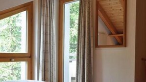 A bedroom with a bed, large windows, and a wooden ceiling. - Chesa Semnadur H8 by Interhome (Sils Maria)
