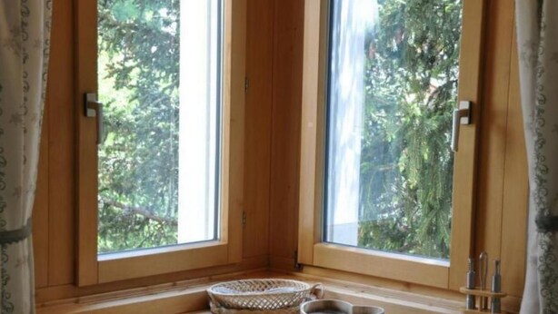 A corner room with a large window, a small wooden table, and two woven baskets. - Chesa Semnadur H8 by Interhome (Sils Maria)