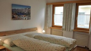 Une chambre avec deux lits, une fenêtre avec des rideaux, un tableau au mur et une table de chevet.