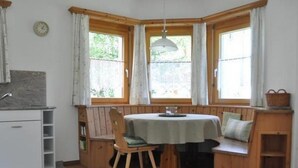 Une pièce chaleureuse avec un banc en bois, une table et une fenêtre avec des rideaux.
