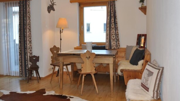 Una habitación acogedora con una mesa de comedor de madera, sillas, un sofá y un tapiz de cuero de vaca.