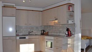 Una cocina moderna con armarios de madera clara, horno integrado y cafetera.