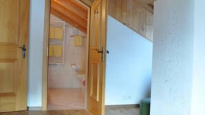 A bedroom with wooden ceiling beams, a bed, and a green ottoman. - Chesa Sunasain V11 by Interhome (Sils Maria)