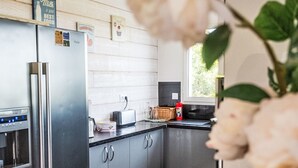 Moderni keittiö, jossa on ruostumattomasta teräksestä valmistettu jääkaappi, leivänpaahdin ja ikkuna, josta avautuu näkymä vehreään maisemaan.