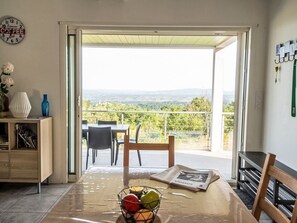 A dining area with a table, chairs, and a view of the countryside through an open door. - Ein gemütliches Nest im Herzen der Ardèche Méridionnale by Interhome (Largentière)