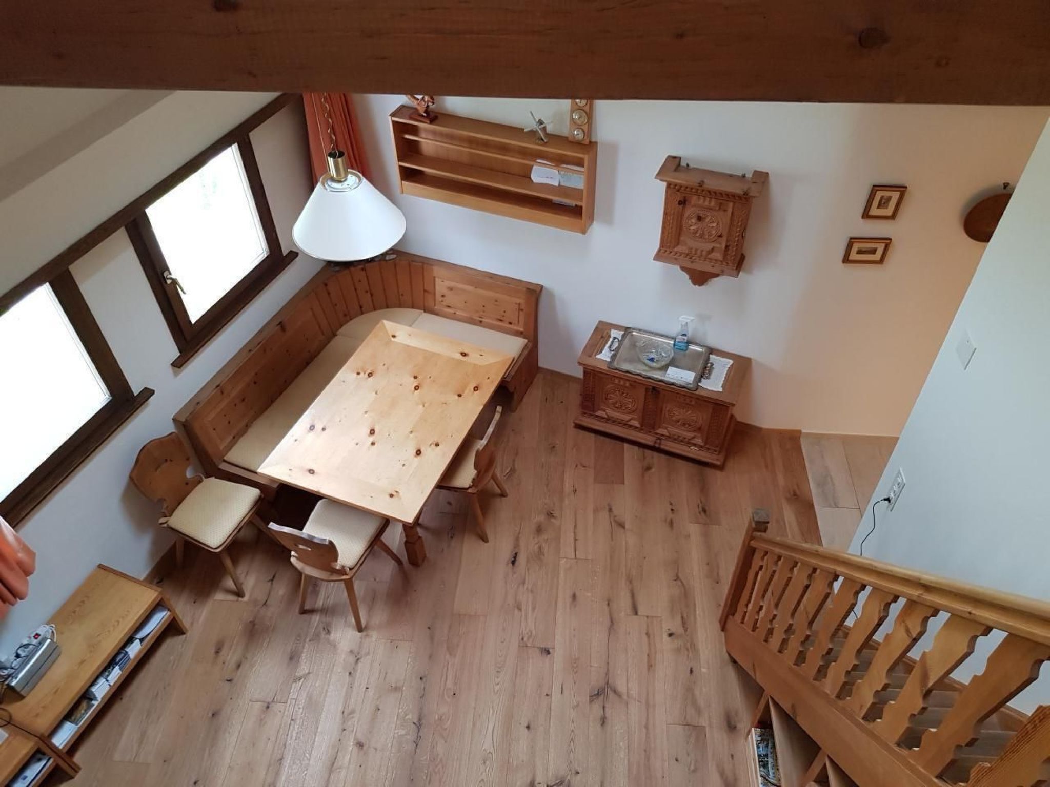 Ein Holzesstisch mit Stühlen, eine Pendelleuchte, ein Holzschrank und eine Treppe.
