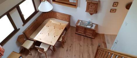 Ein Holzesstisch mit Stühlen, eine Pendelleuchte, ein Holzschrank und eine Treppe.