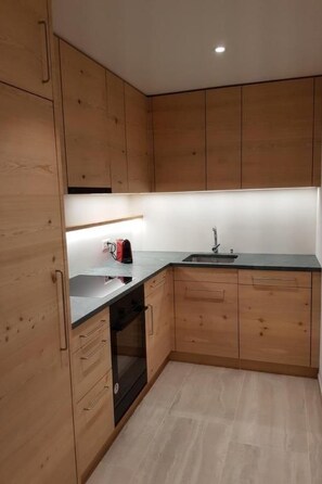 Een koelkast, een oven, een vaatwasser, kookgerei, borden en bestek