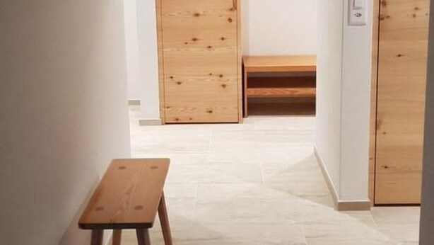 Een gang met houten deuren, een bankje en een kleine tafel.