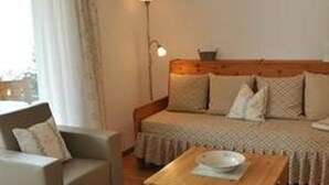 A cozy room with a sofa, a wooden table, and a lamp. - Apartment  by Interhome (Sils Maria)