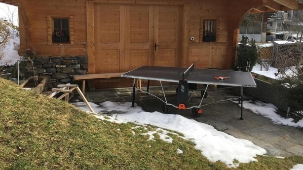 Une cabane en bois avec une table de ping-pong devant.